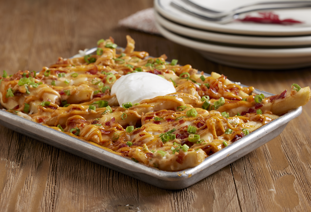 Loaded Nachos on a pan with plates in the background